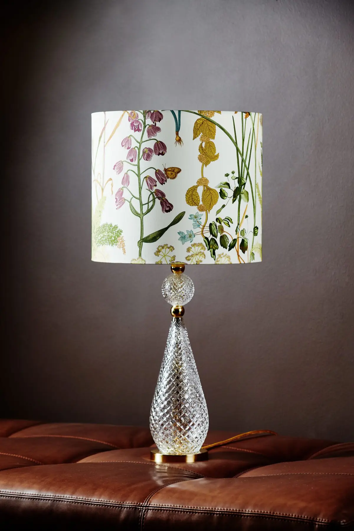 Tischleuchte mit floral gemustertem Schirm auf einem Ledersofa