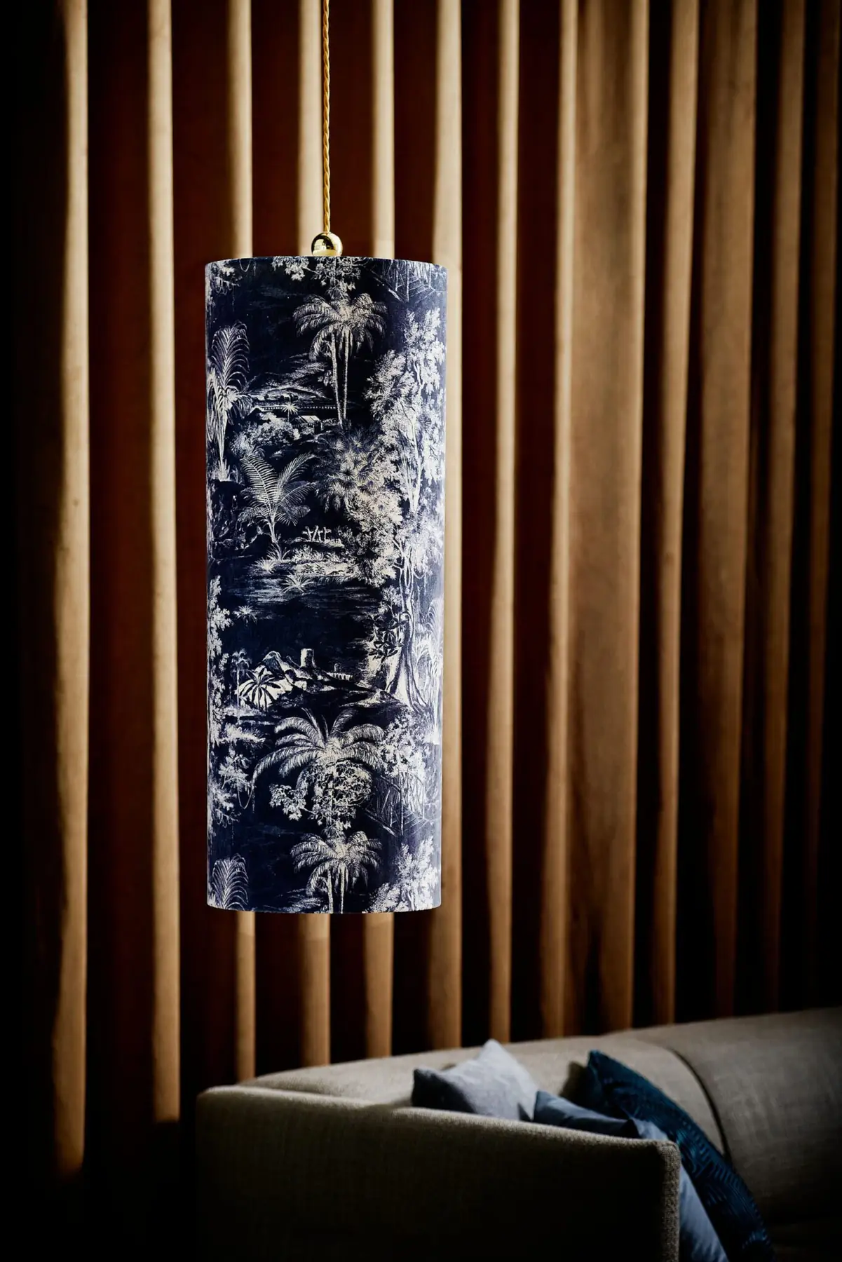 Pendelleuchte mit blau gemustertem Schirm vor einer Holzlamellenwand