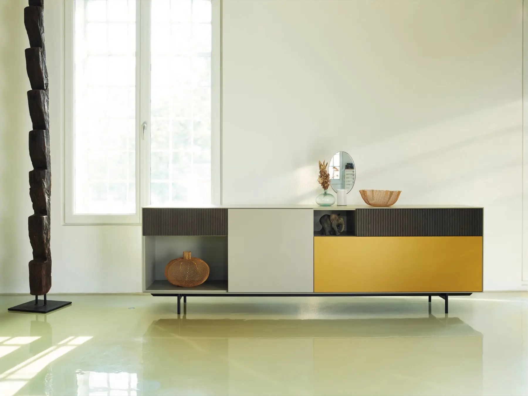 Sideboard mit gelben Fronten vor einer hohen Fensterfront