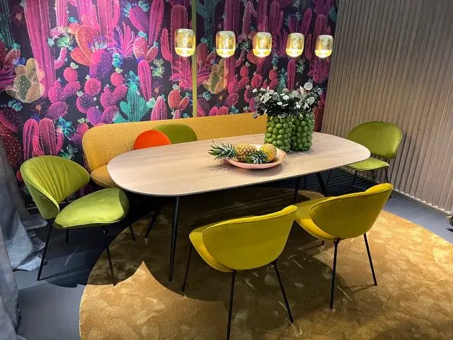 Essplatz mit grünen Stühlen und Sitzbank vor einer floralen Mustertapete