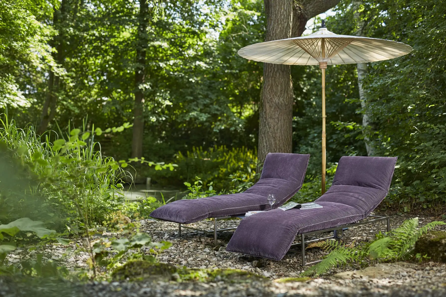 Zwei violette Outdoor-Liegen Lettino unter einem Sonnenschirm