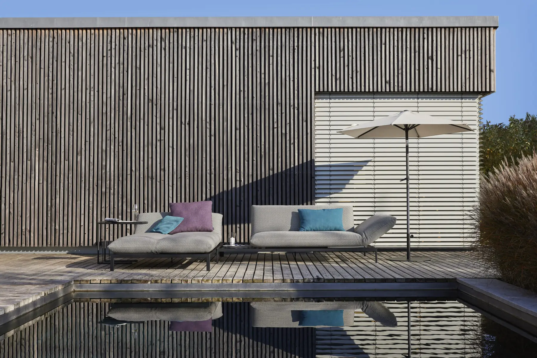 Outdoor-Lounge Kaya mit Sonnenschirm vor einer Holzfassade