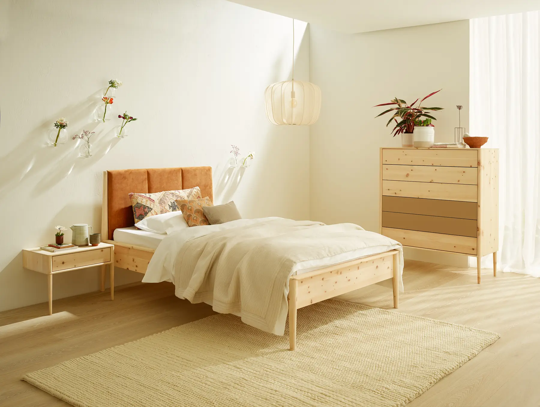 Schlafzimmer mit Massivholzbett, Nachtkästchen und schmaler Kommode