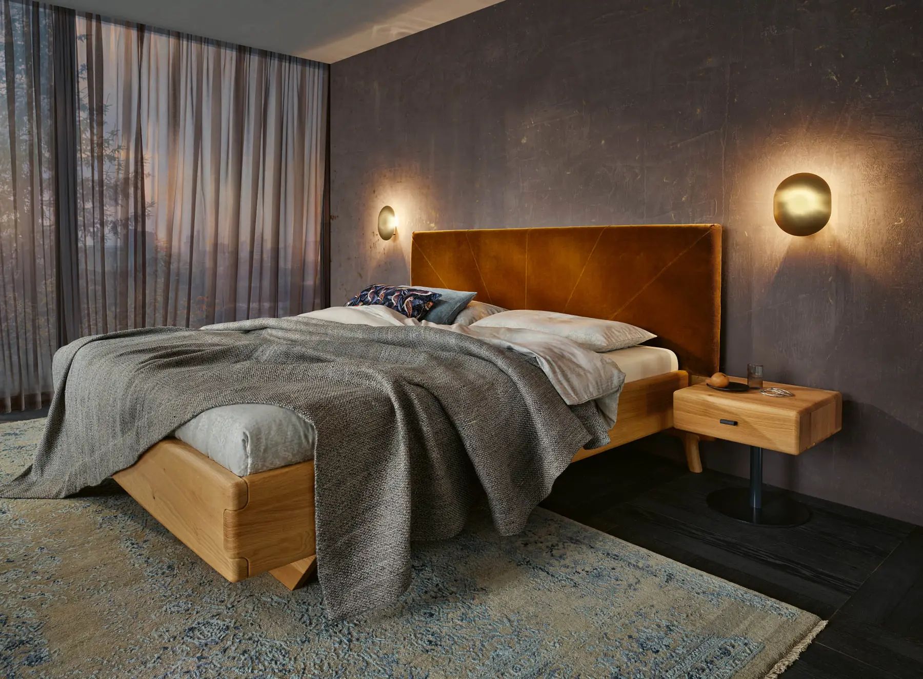 Bett mit ockerfarbenem Samtkopfteil zwischen zwei goldenen Wandleuchten