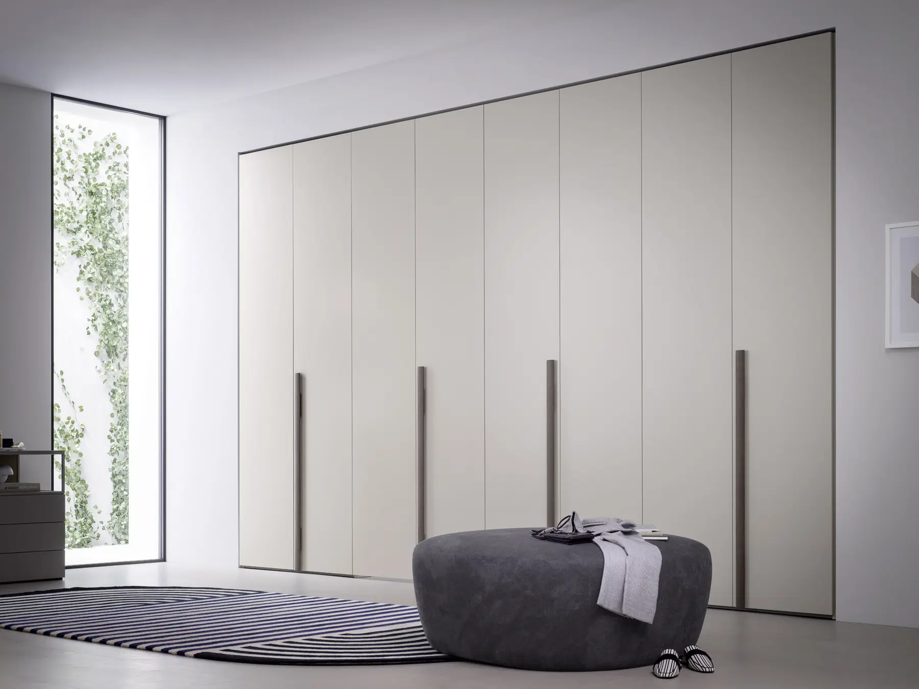 Geschlossene Schrankfront in Creme mit Pouf und Teppich davor