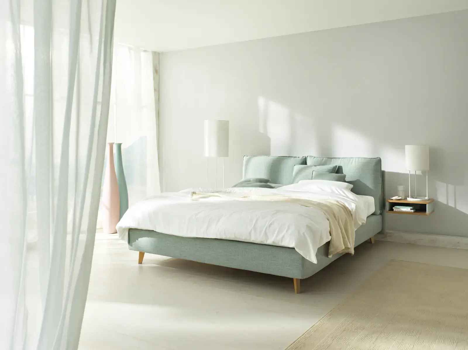 Mintgrünes Boxspringbett Arte mit filigranen Füßen in einem hellen Schlafzimmer