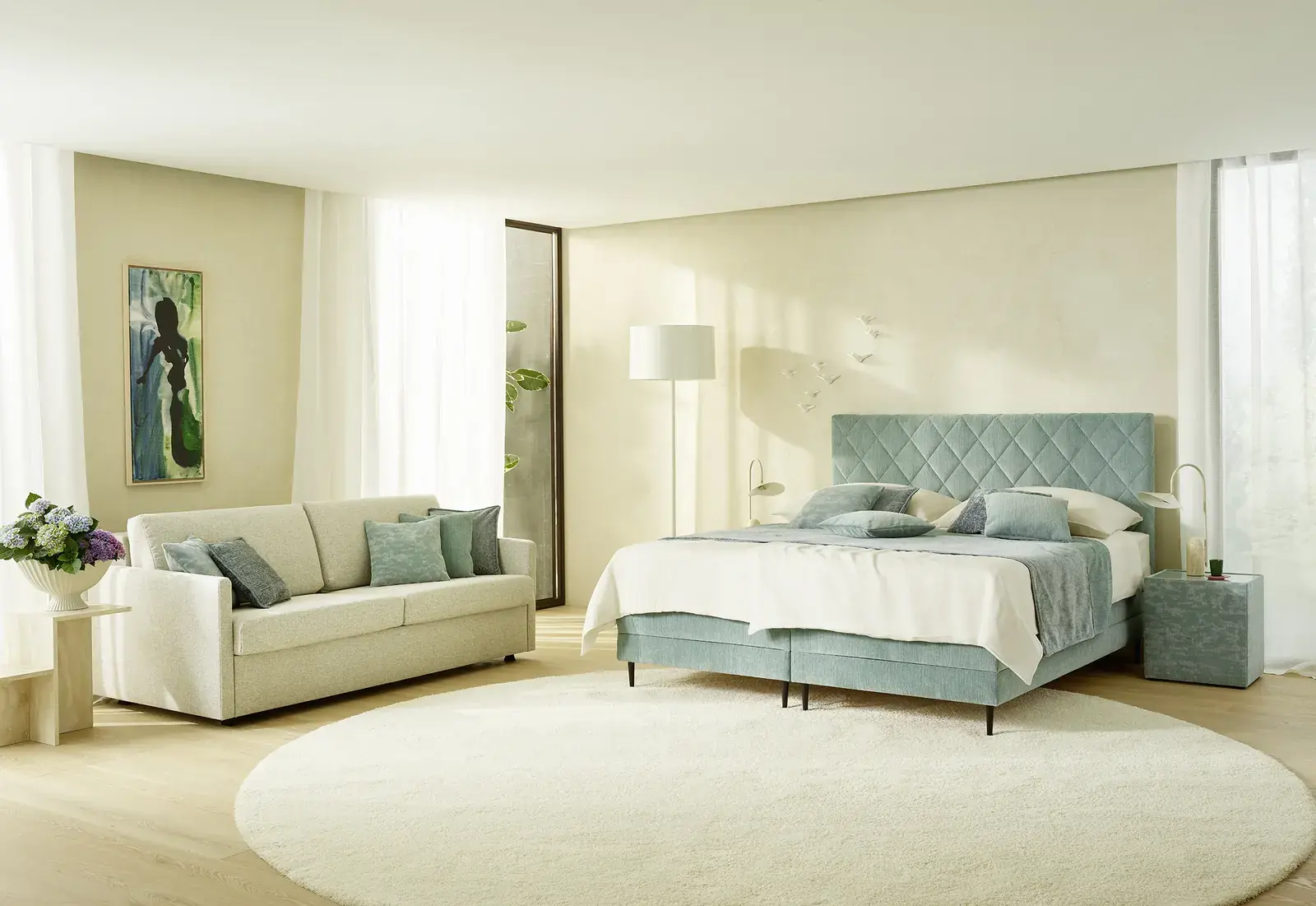Mintgrünes Boxspringbett mit gepolstertem Kopfteil und Sofa im Schlafzimmer