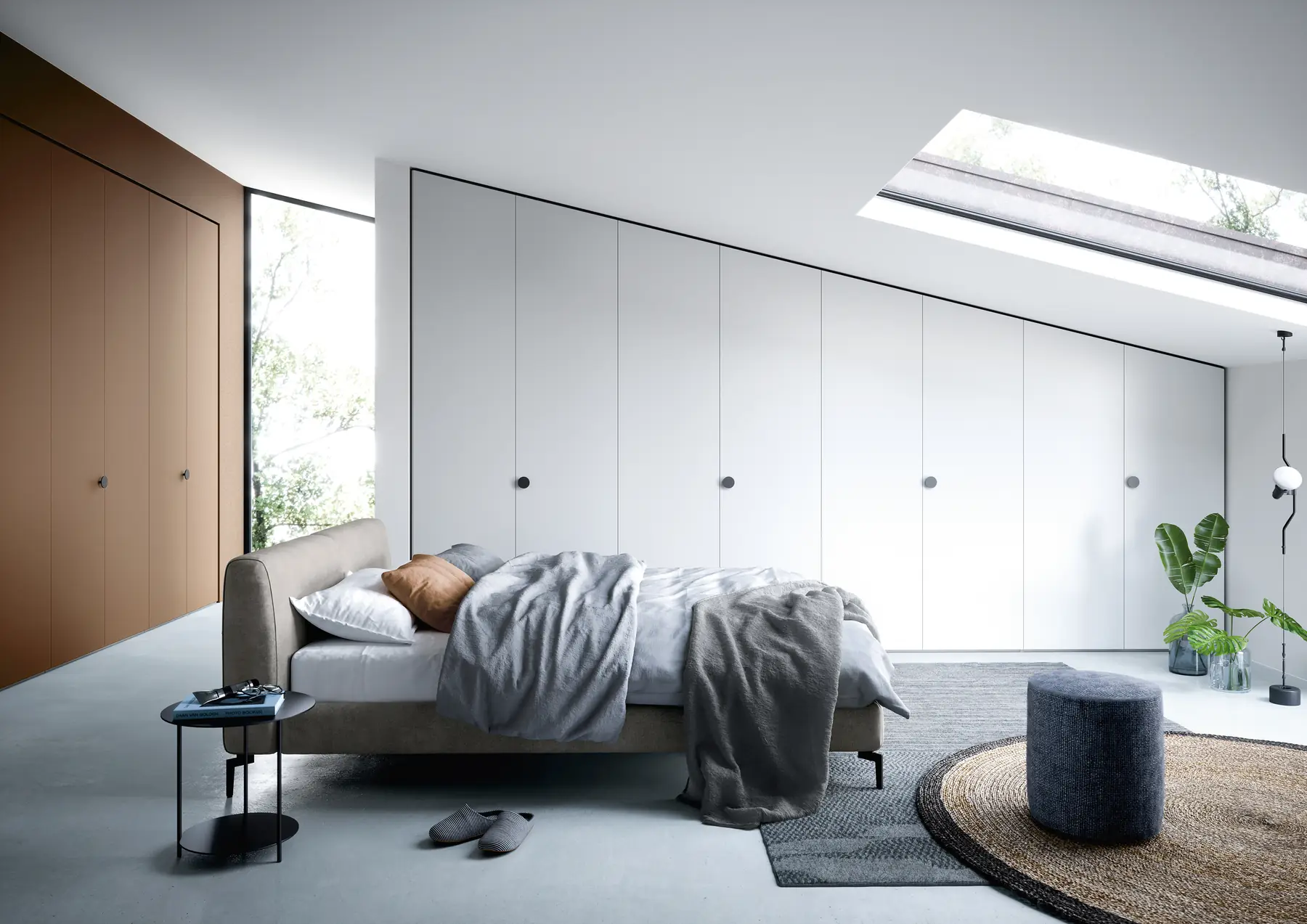 Schlafzimmer mit Polsterbett und raumhoher Schrankwand unter Dachfenstern