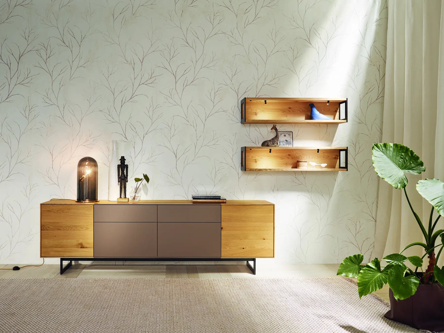 Sideboard mit dunklen Fronten, Holzrahmen und zwei beleuchteten Wandregalen