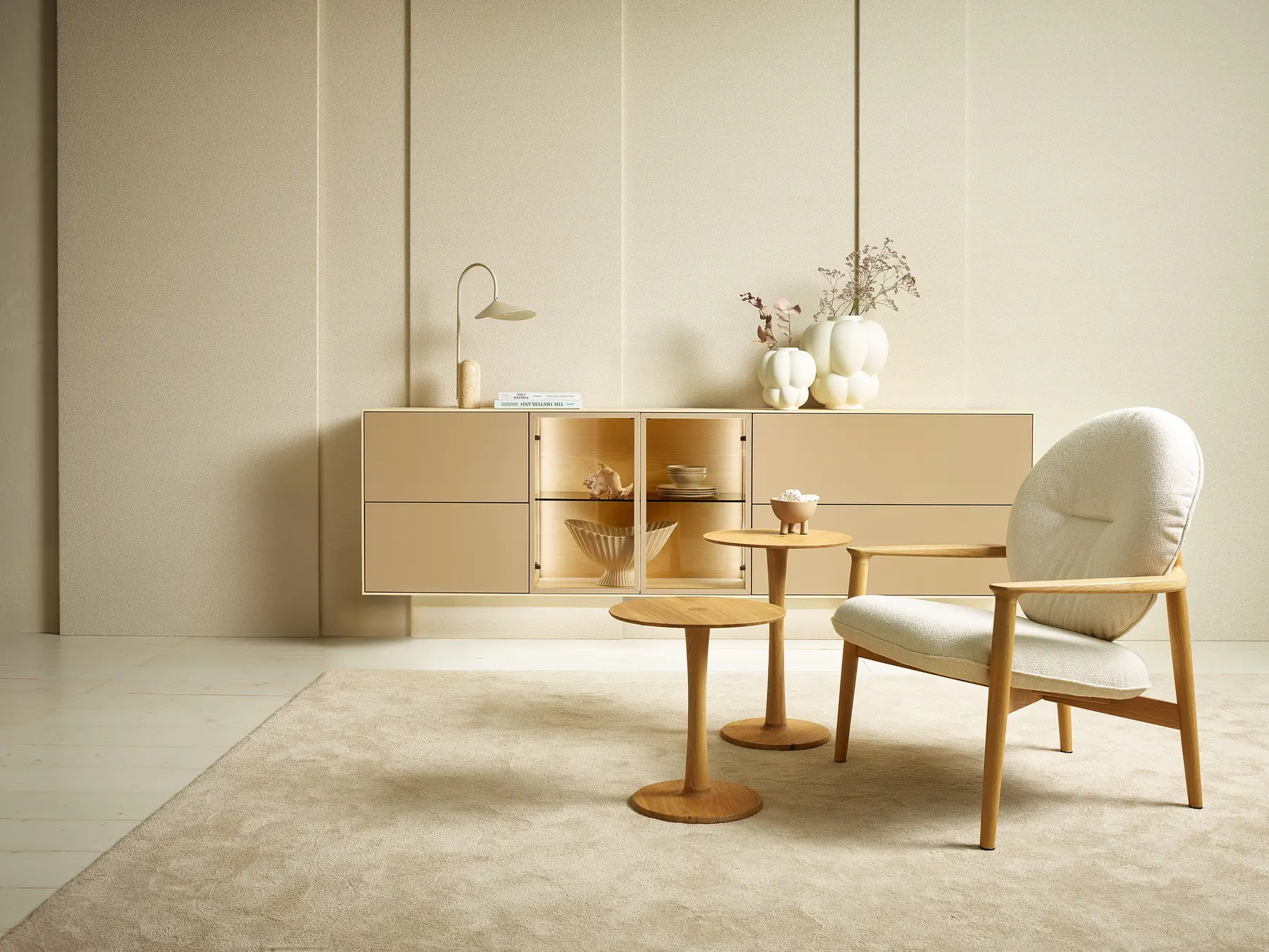 Beigefarbenes Sideboard mit offenen Holzfächern hinter einem Sessel und Beistelltischen