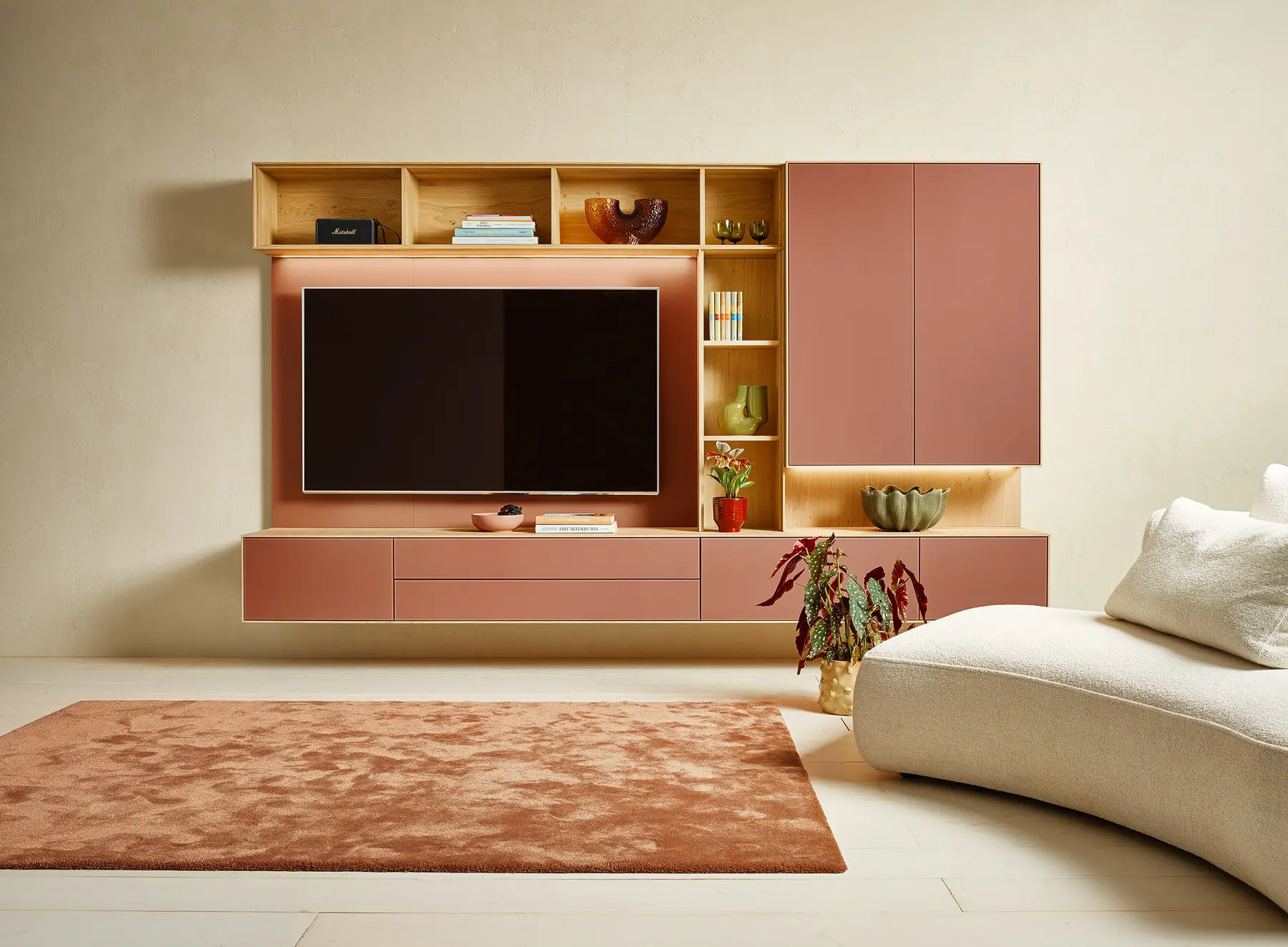 Wohnwand mit rosafarbenen Fronten, offenen Holzfächern und integriertem Fernseher