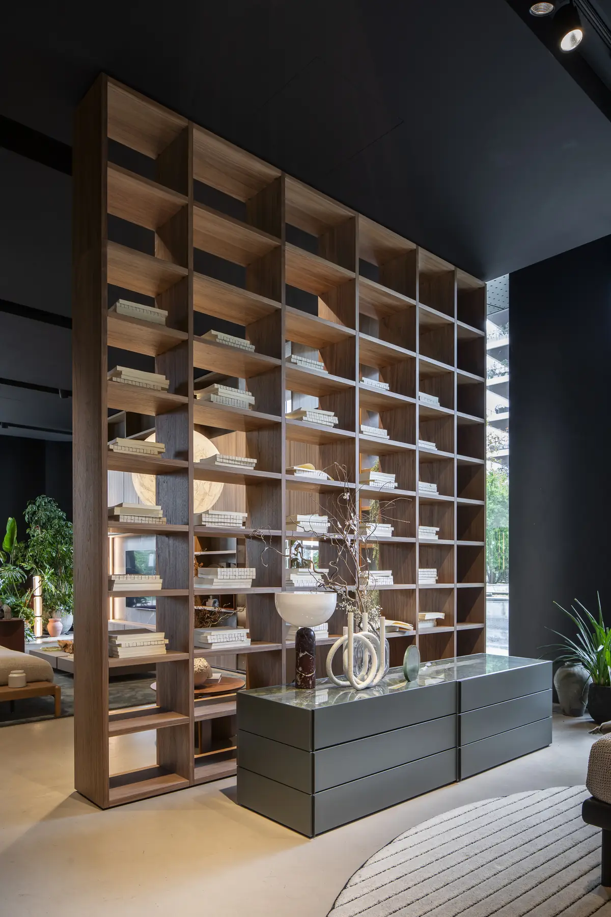 Raumhohe Bücherwand aus Holz mit dunklen Unterschränken und Beleuchtung