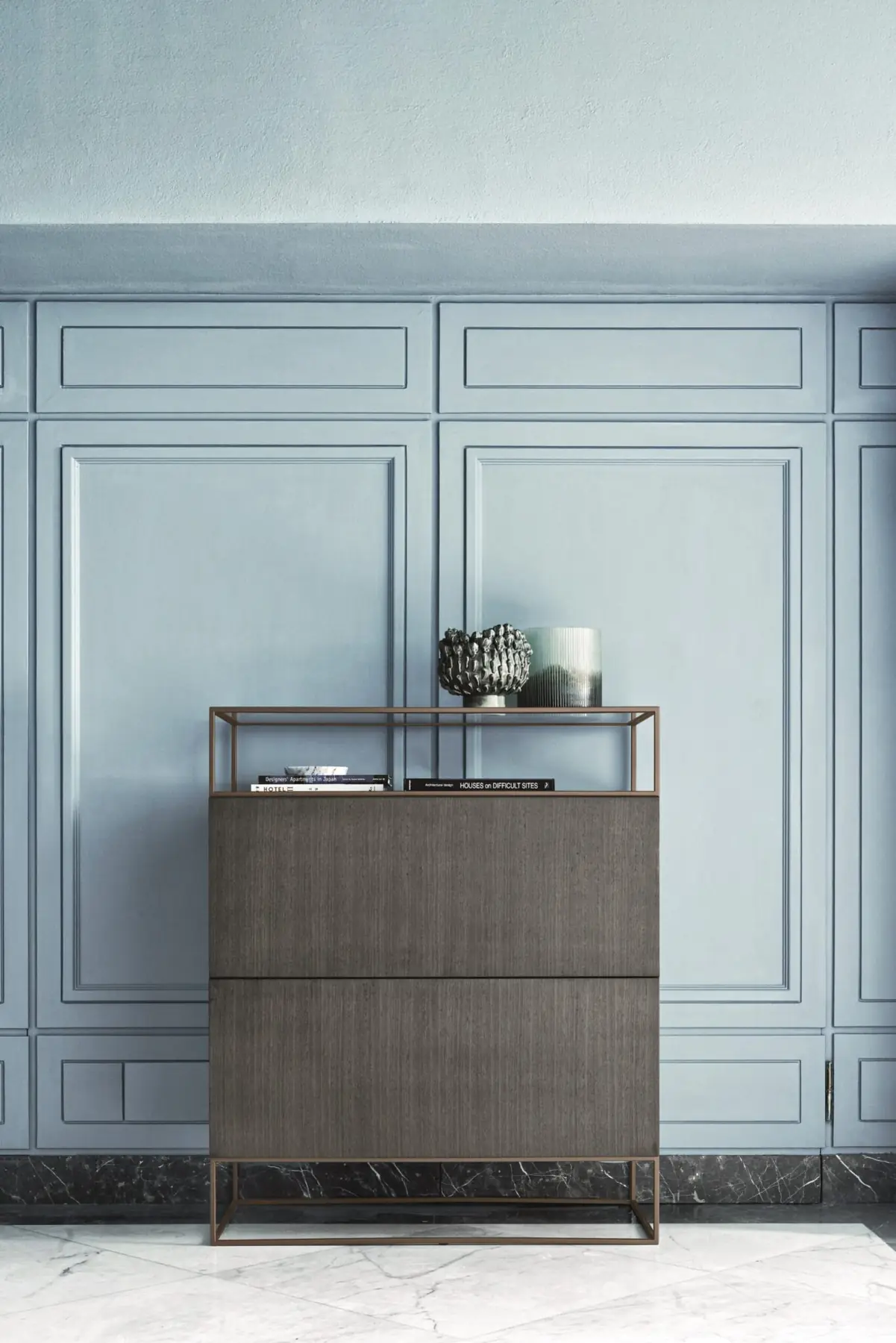 Highboard mit Glasvitrine vor einer blauen Wandvertäfelung
