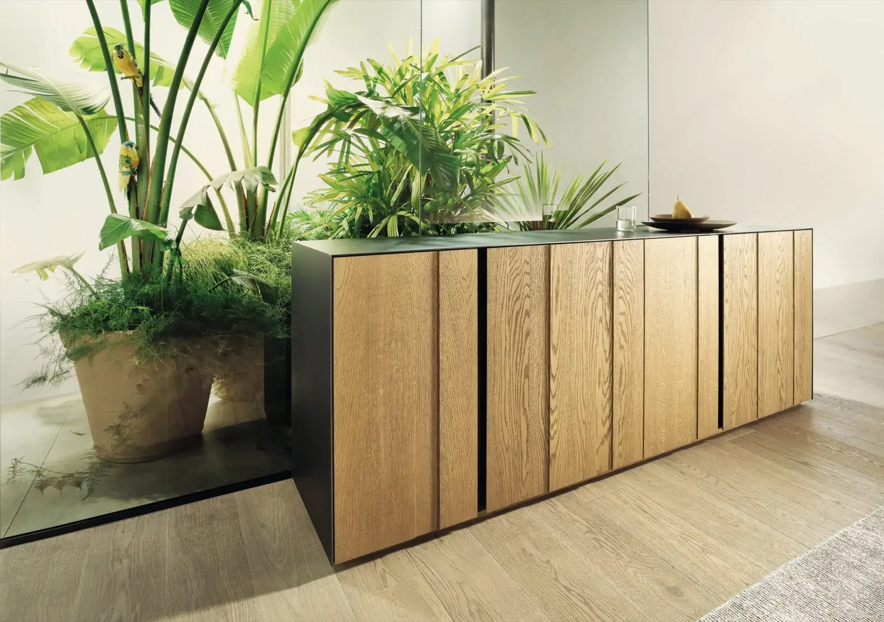 Sideboard aus Eiche vor großen Grünpflanzen