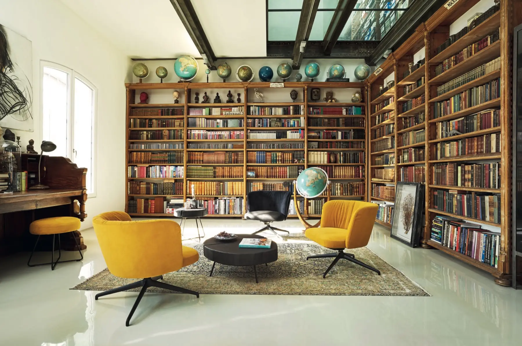 Raumhohe Bibliothekswand mit Büchern und gelben Drehsesseln